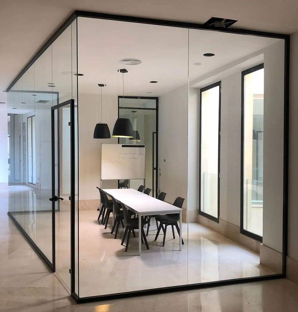Sala riunioni chiusa da pareti vetrate con telaio nero in un open space