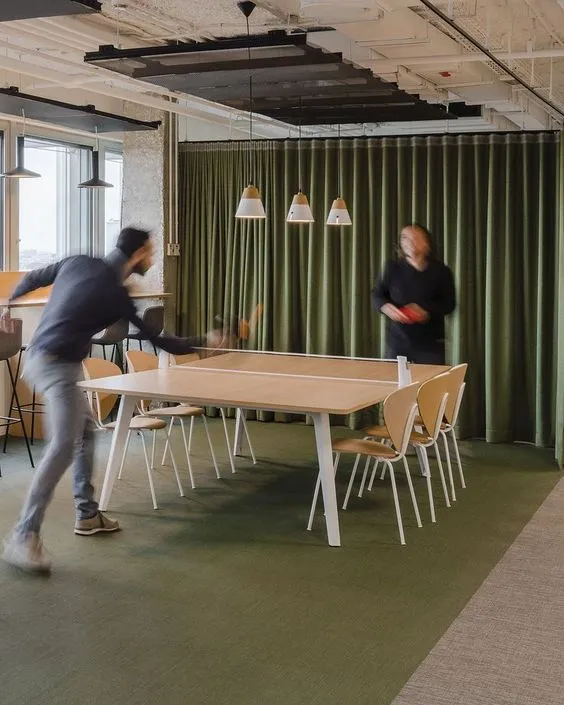 Team in pausa a giocare a ping pong in un'area relax aziendale